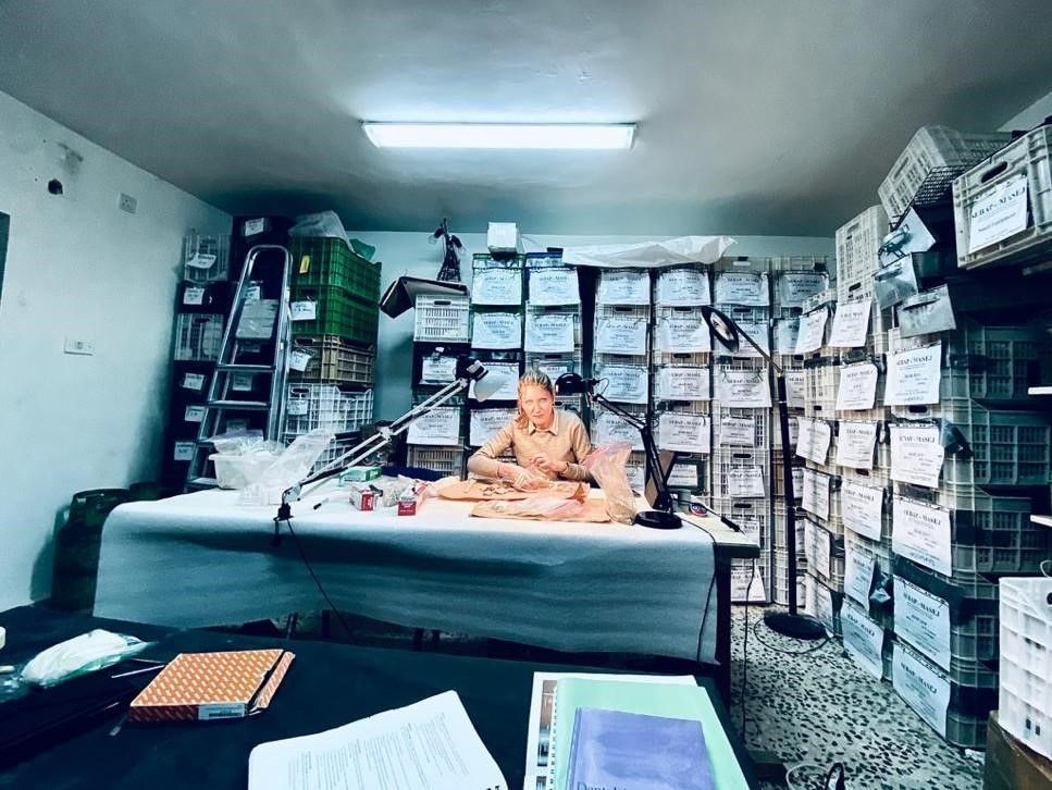 Person sitting at a desk surrounded by labeled containers lining the walls.